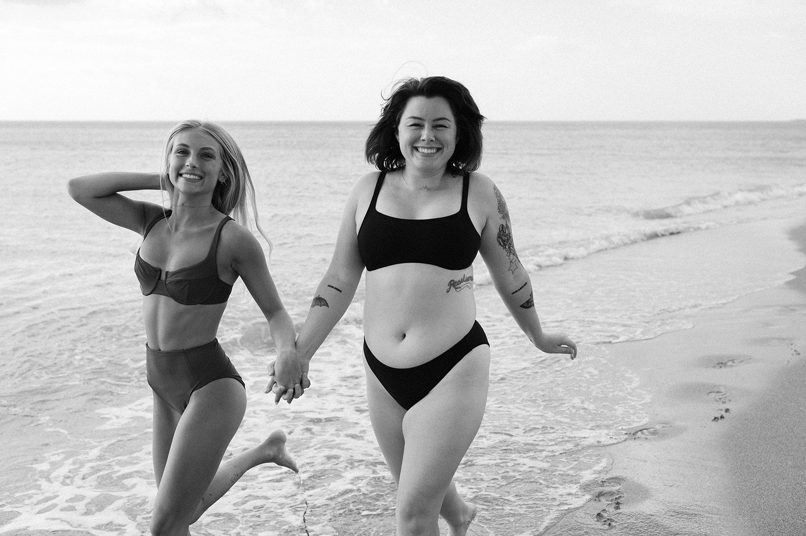 two models running by the camera laughing and holding hands